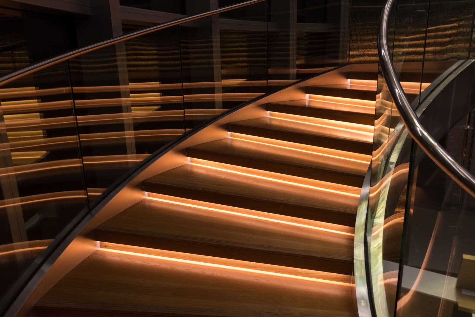 Illuminated curved staircase with a glass balustrade